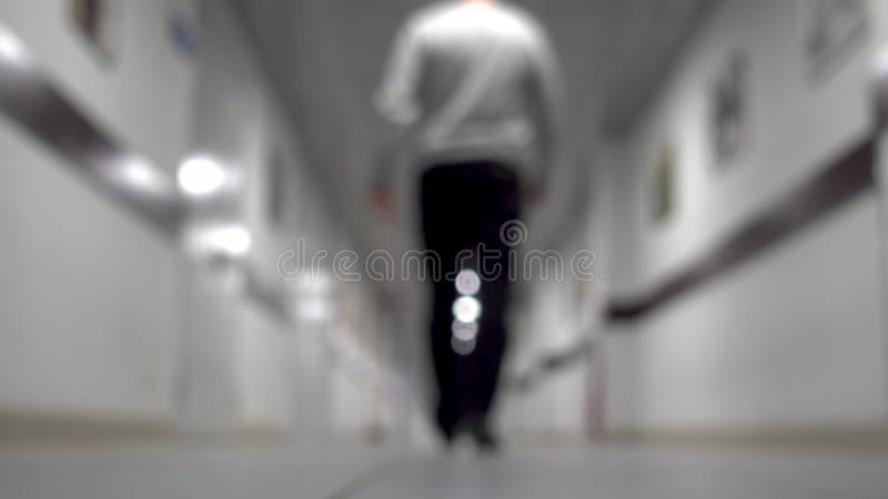 Ένα άτομο περπατά κάτω από το διάδρομο ανασκόπηση που θολώνεται Νεαρός άνδρας που περπατά κάτω από το μακρύ διάδρομο