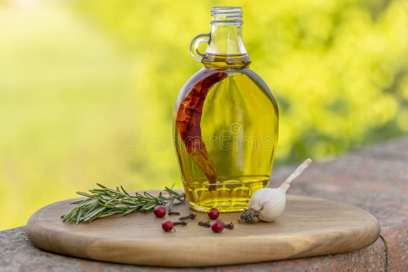ένα γυάλινο πλακίδιο που περιέχει εξαιρετικό παρθένο ελαιόλαδο αρωματισμένο με κόκκινη πιπεριά τσίλι βρίσκεται σε ξύλινη επιφάνεια στοκ εικόνα