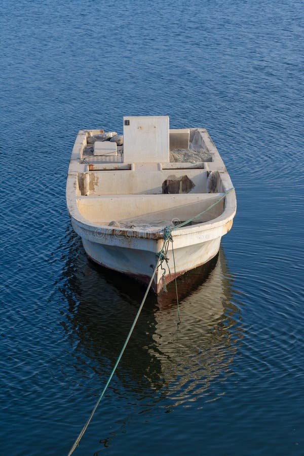 Ένα ηλιοβασίλεμα βραδιού με μια αγροτική βάρκα κοιτάγματος που απορροφά τις ακτίνες στο μπλε νερό στοκ εικόνες με δικαίωμα ελεύθερης χρήσης Ένα ηλιοβασίλεμα βραδιού με μια αγροτική βάρκα κοιτάγματος που απορροφά τις ακτίνες στο μπλε νερό στοκ εικόνες με δικαίωμα ελεύθερης χρήσης