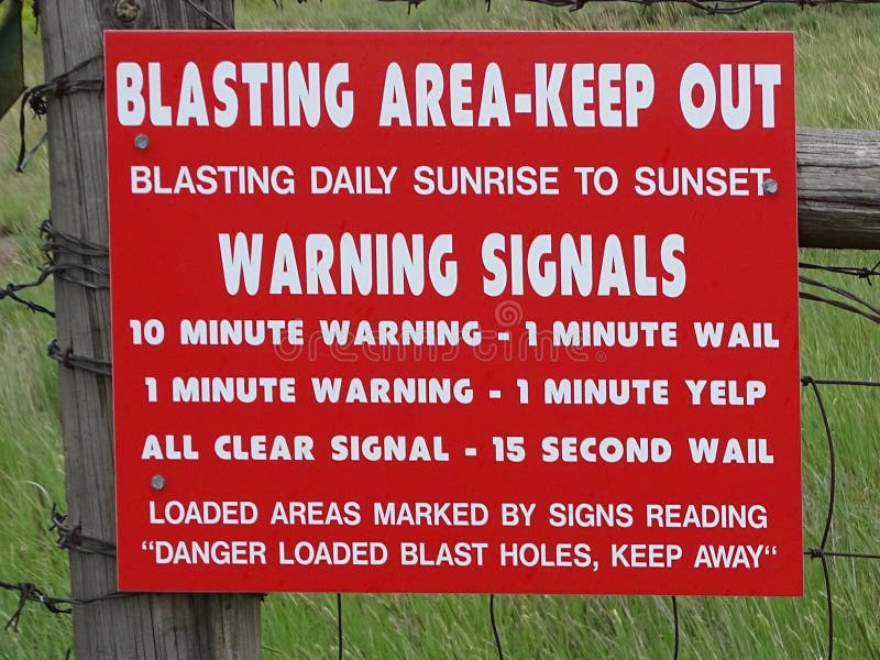 A red warning sign giving information on rock blasting in the area. A red warning sign giving information on rock blasting in the area