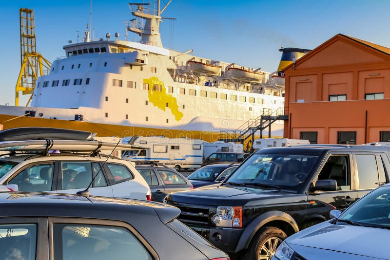 Ένα μεγάλο κρουαζιερόπλοιο είναι δεμένο δίπλα σε ένα κτίριο με πολλά αυτοκίνητα σταθμευμένα για στοκ φωτογραφία με δικαίωμα ελεύθερης χρήσης