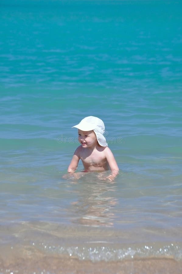 Ένα μικρό κορίτσι σε ένα άσπρο καπέλο κολυμπά στη θάλασσα μια ηλιόλουστη ημέρα στοκ εικόνα Ένα μικρό κορίτσι σε ένα άσπρο καπέλο κολυμπά στη θάλασσα μια ηλιόλουστη ημέρα στοκ εικόνα