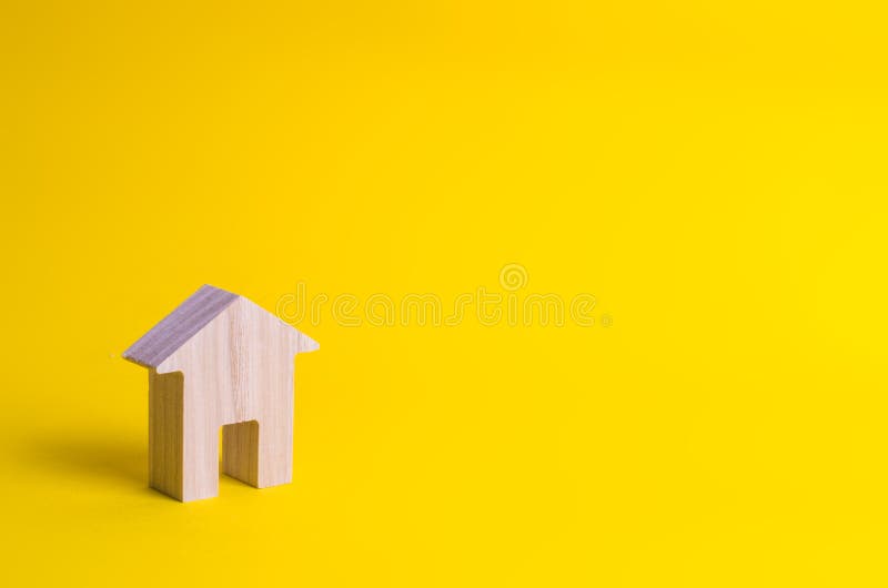 Ένα μικρό ξύλινο σπίτι στέκεται σε ένα κίτρινο υπόβαθρο στοκ φωτογραφία με δικαίωμα ελεύθερης χρήσης