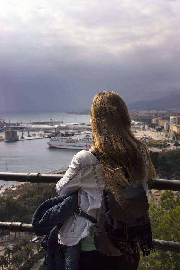 Ένα μόνο κορίτσι στέκεται σε έναν λόφο και εξετάζει το όμορφο πανόραμα της ισπανικής πόλης της Μάλαγας μια θερμή ηλιόλουστη ημέρα στοκ εικόνες με δικαίωμα ελεύθερης χρήσης Ένα μόνο κορίτσι στέκεται σε έναν λόφο και εξετάζει το όμορφο πανόραμα της ισπανικής πόλης της Μάλαγας μια θερμή ηλιόλουστη ημέρα στοκ εικόνες με δικαίωμα ελεύθερης χρήσης