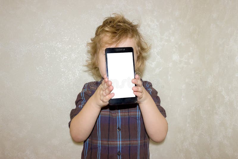 Ένα παιδί αγοριών εξετάζει τη κάμερα ενός smartphone, παρουσιάζει την οθόνη στοκ φωτογραφία Ένα παιδί αγοριών εξετάζει τη κάμερα ενός smartphone, παρουσιάζει την οθόνη στοκ φωτογραφία