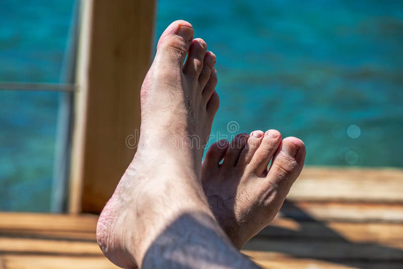 ένα πόδι δίπλα στη θάλασσα. ένα κοντινό πλάνο από τα πόδια και τα πόδια ενός ανθρώπου που αναπαύονται στη ζεστή άμμο από τη θάλασσα, αιχμαλωτίζοντας την ουσία της χαλάρωσης και τον τρόπο ζωής της παραλίας