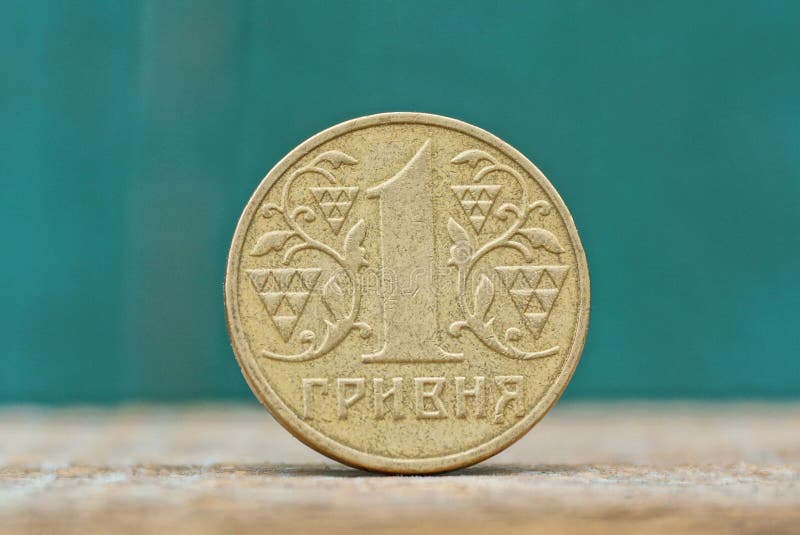 Ένα στρογγυλό κίτρινο ουκρανικό νόμισμα hryvnia σε έναν γκρίζο πίνακα σε ένα πράσινο υπόβαθρο στοκ εικόνες Ένα στρογγυλό κίτρινο ουκρανικό νόμισμα hryvnia σε έναν γκρίζο πίνακα σε ένα πράσινο υπόβαθρο στοκ εικόνες