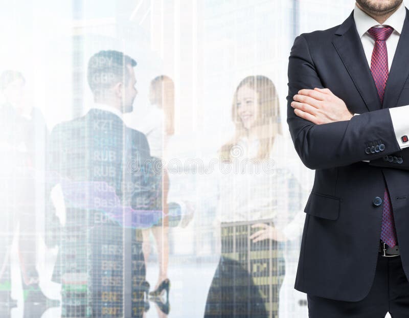 A body in a formal suit with crossed hands. A figures of the young professionals in formal clothes on the background. A body in a formal suit with crossed hands. A figures of the young professionals in formal clothes on the background.