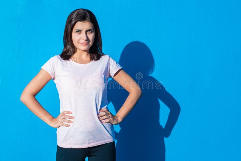Ένα όμορφο χαρούμενο νεαρό κορίτσι με περιστασιακά ρούχα που στέκονταν απομονωμένο πάνω από το μπλε φόντο μια ηλιόλουστη μέρα Η γ στοκ φωτογραφία Ένα όμορφο χαρούμενο νεαρό κορίτσι με περιστασιακά ρούχα που στέκονταν απομονωμένο πάνω από το μπλε φόντο μια ηλιόλουστη μέρα Η γ στοκ φωτογραφία