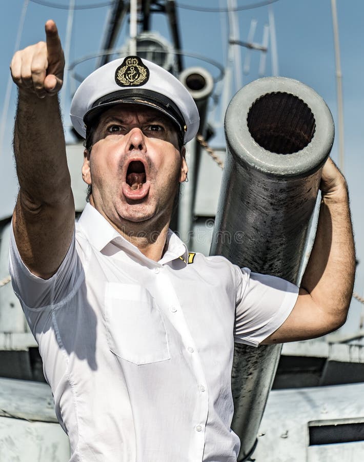 A navy officer standing beside gun and pointing his finger ahead.The captain issues an order to attack and shoot from a ship`s cannon. A navy officer standing beside gun and pointing his finger ahead.The captain issues an order to attack and shoot from a ship`s cannon