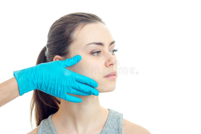 Ένας γιατρός σε ένα μπλε γάντι αγγίζει το μάγουλο ενός νέου κοριτσιού χωρίς makeup που κοιτάζει προς την κινηματογράφηση σε πρώτο στοκ φωτογραφία με δικαίωμα ελεύθερης χρήσης Ένας γιατρός σε ένα μπλε γάντι αγγίζει το μάγουλο ενός νέου κοριτσιού χωρίς makeup που κοιτάζει προς την κινηματογράφηση σε πρώτο στοκ φωτογραφία με δικαίωμα ελεύθερης χρήσης