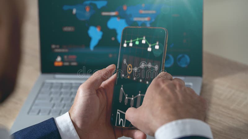 Ένας επιχειρηματίας κοιτάζει τα γραφήματα στο τηλέφωνο και το φορητό υπολογιστή του Έννοια: ανάπτυξη επιχειρήσεων, αύξηση κερδών στοκ φωτογραφίες