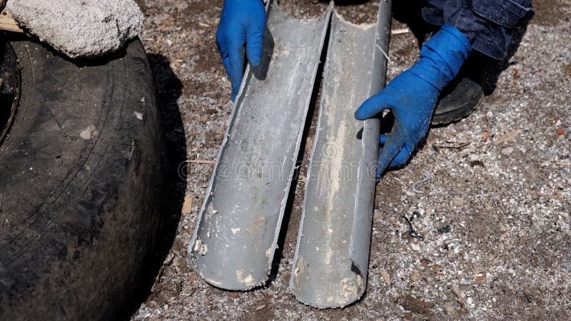 ένας υδραυλικός με λαστιχένια γάντια κόβει έναν πλαστικό σωλήνα αποχέτευσης κατά μήκος σε δύο μισά. στοκ εικόνες