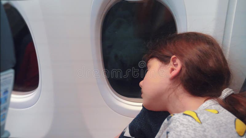 Έννοια αεροσκαφών αεροπορίας Νέος ύπνος μικρών κοριτσιών στη συνεδρίαση αεροπλάνων από το παράθυρο Πτήση τη νύχτα κοντά