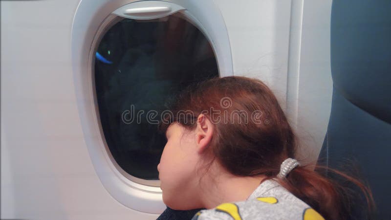 Έννοια αεροσκαφών αεροπορίας Νέος ύπνος μικρών κοριτσιών στη συνεδρίαση αεροπλάνων από το παράθυρο Τρόπος ζωής πτήσης τη νύχτα