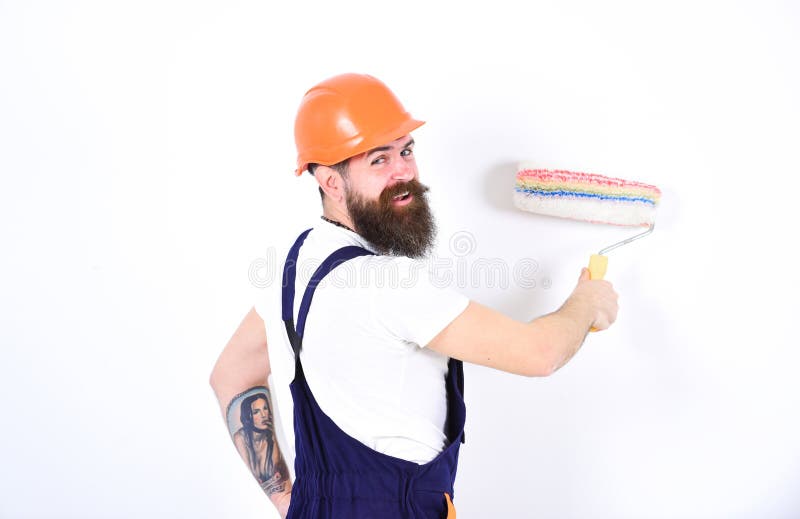 Έννοια εγχώριου redecoration Πίσω τοίχος ζωγραφικής οικοδόμων χαμόγελου στροφής με τον κύλινδρο χρωμάτων Απομονωμένο άτομο στο πο στοκ φωτογραφία