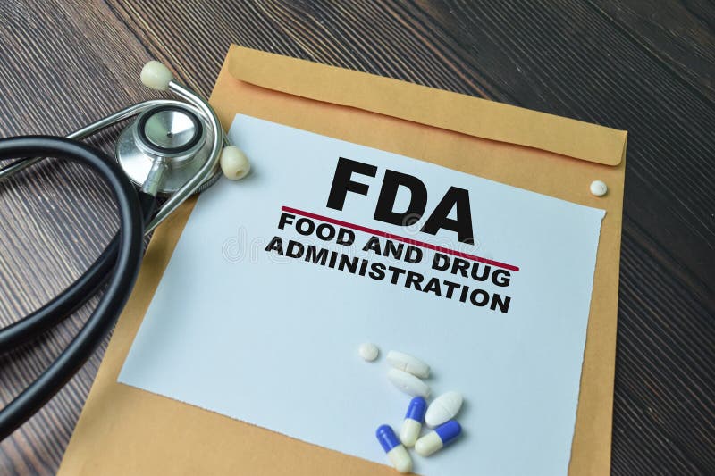 έννοια του fda κείμενο για τη χορήγηση τροφίμων και φαρμάκων σε έγγραφο πάνω από καφέ περιτύλιγμα απομονωμένο σε ξύλινο τραπέζι στοκ εικόνες