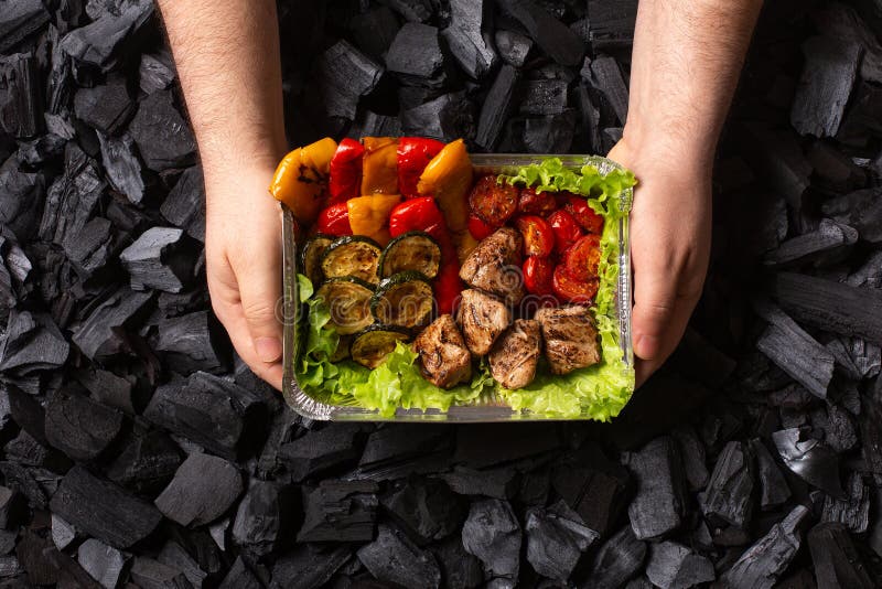 έτοιμο shish kebab. τμήμα κρέατος και λαχανικών που έχουν υποστεί ψήσιμο σε δοχείο μιας χρήσης σε αρσενικά χέρια.