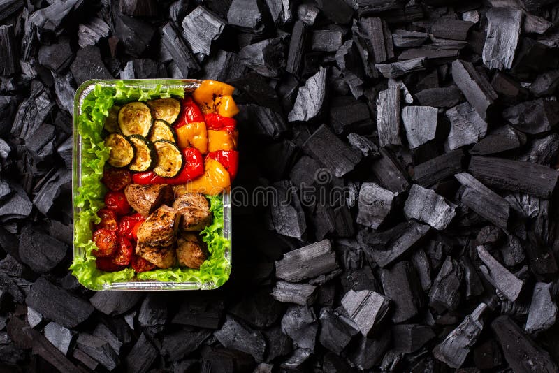 έτοιμο shish kebab. τμήμα κρέατος και λαχανικών που έχουν υποστεί ψήσιμο σε περιέκτη μιας χρήσης στο φόντο του άνθρακα. χώρος αντι