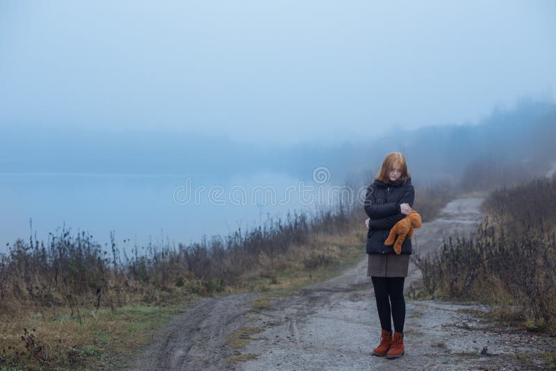 έφηβο κορίτσι με αρκουδάκι στο δρόμο δίπλα στη λίμνη ομίχλη. αντίληψη περί εφηβικών και εφηβικών προβλημάτων