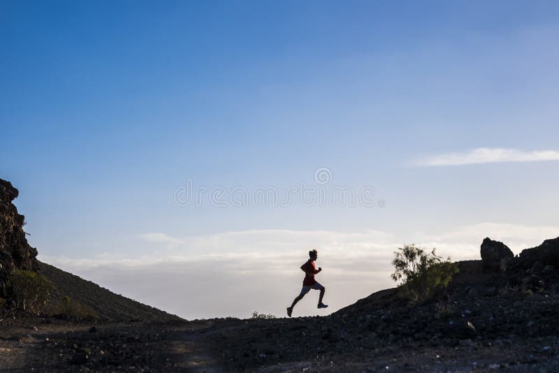 Teenager running alone in mountain with mountains at the background and beautiful sunset - ftiness guy jogging isolated - sunny day and trip with no stop. Teenager running alone in mountain with mountains at the background and beautiful sunset - ftiness guy jogging isolated - sunny day and trip with no stop