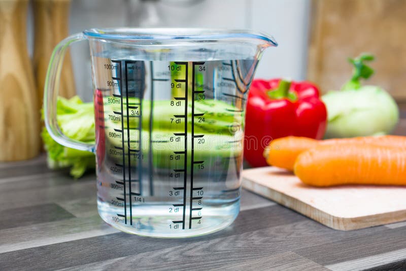 1 Liter / 1000ml / 10dl Of Water In Measuring Cup On A Kitchen Counter With Vegetables. 1 Liter / 1000ml / 10dl Of Water In Measuring Cup On A Kitchen Counter With Vegetables