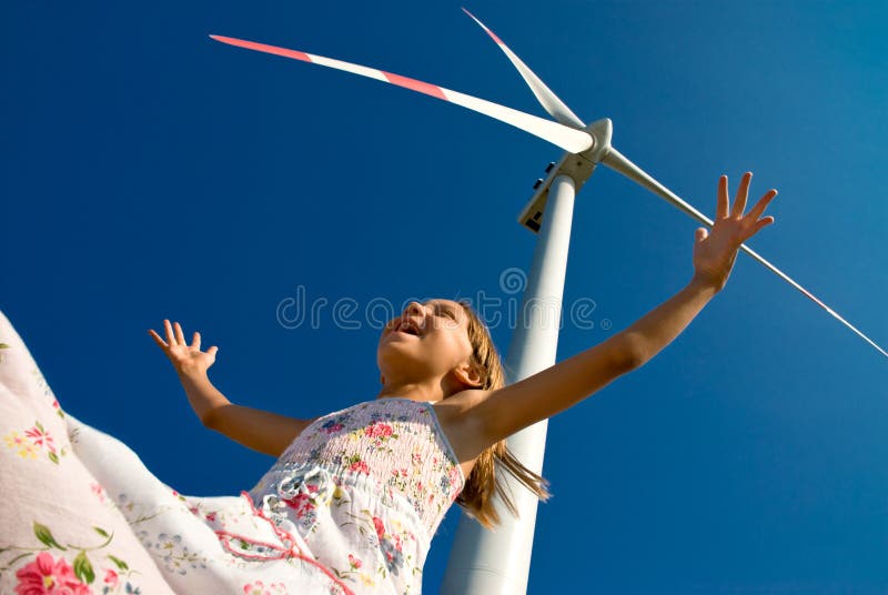 Child playing with the wind near a wind turbine. Child playing with the wind near a wind turbine