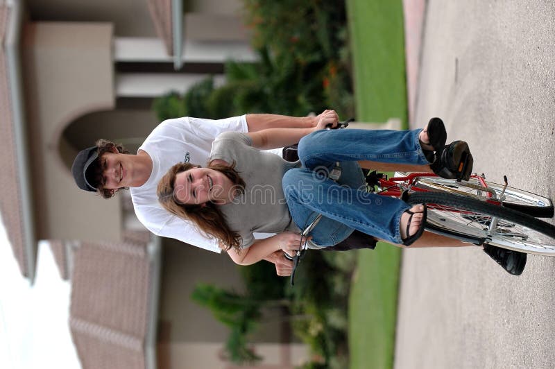 A teenage couple riding a bike together with the girl on the handle bars. A teenage couple riding a bike together with the girl on the handle bars.