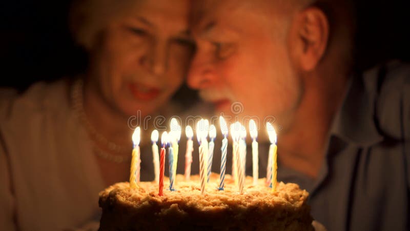 Αγαπώντας την ανώτερη επέτειο εορτασμού ζευγών με το κέικ στο σπίτι το βράδυ φυσώντας κεριά έξω