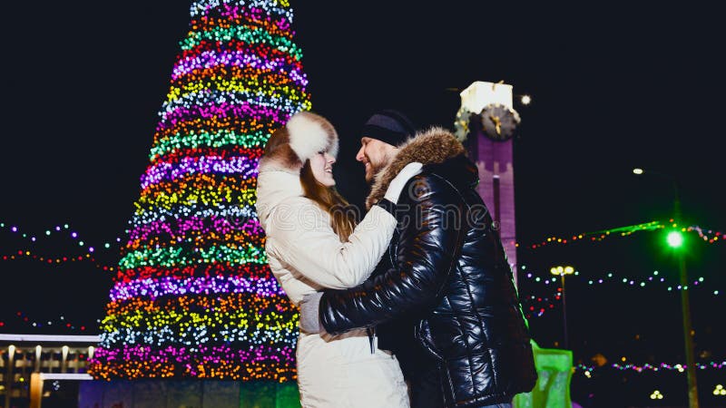 Happy young men and women cuddling under chimes on Christmas night. Happy young men and women cuddling under chimes on Christmas night