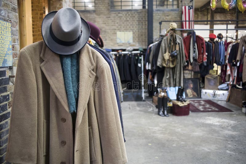 London, UK - 13 February, 2020 Spitalfields flea market. Woolen cashmere men`s coat with felt hat on the background of rows with clothes for sale. London, UK - 13 February, 2020 Spitalfields flea market. Woolen cashmere men`s coat with felt hat on the background of rows with clothes for sale