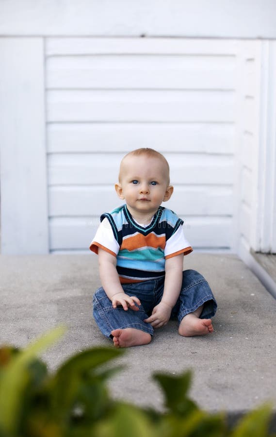 A 6 month old baby boy sitting on a porch. A 6 month old baby boy sitting on a porch.