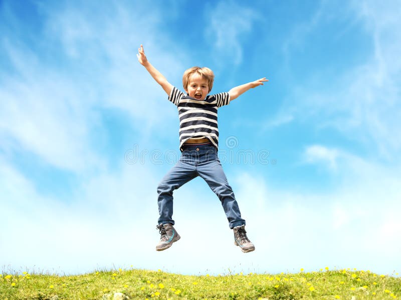 Boy jumping in a meadow at the top of a hill against a blue sky. Boy jumping in a meadow at the top of a hill against a blue sky