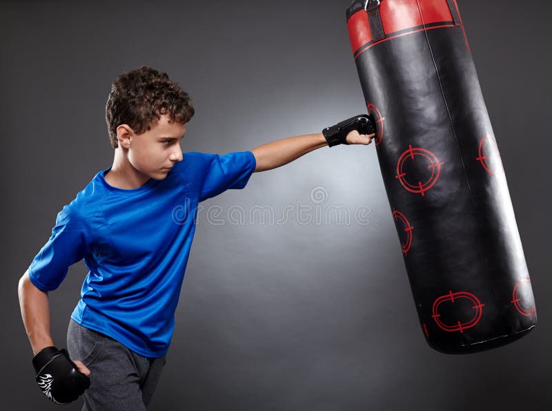 Αγόρι που χτυπά τη punching τσάντα στοκ φωτογραφίες