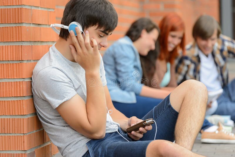 Αγόρι σπουδαστών με τους φίλους ακουστικών έξω από την πανεπιστημιούπολη στοκ εικόνες Αγόρι σπουδαστών με τους φίλους ακουστικών έξω από την πανεπιστημιούπολη στοκ εικόνες