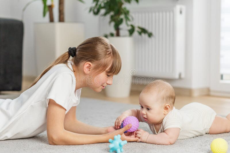 Αδελφή που διδάσκει μωρό με αισθητηριακή σφαίρα. Χρόνος κοιλίας στοκ εικόνα