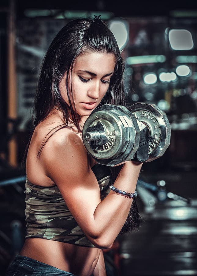 Αθλητική γυναίκα που αντλεί επάνω muscules με τους αλτήρες στοκ φωτογραφία Αθλητική γυναίκα που αντλεί επάνω muscules με τους αλτήρες στοκ φωτογραφία