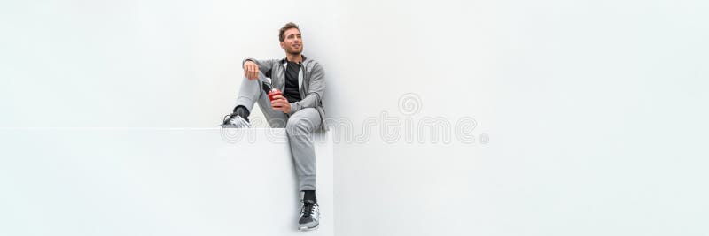 Ftiness sport man drinking smoothie workout banner relaxing at home in gym jogging pants activewear outdoor. Athlete sitting on white background. Ftiness sport man drinking smoothie workout banner relaxing at home in gym jogging pants activewear outdoor. Athlete sitting on white background.