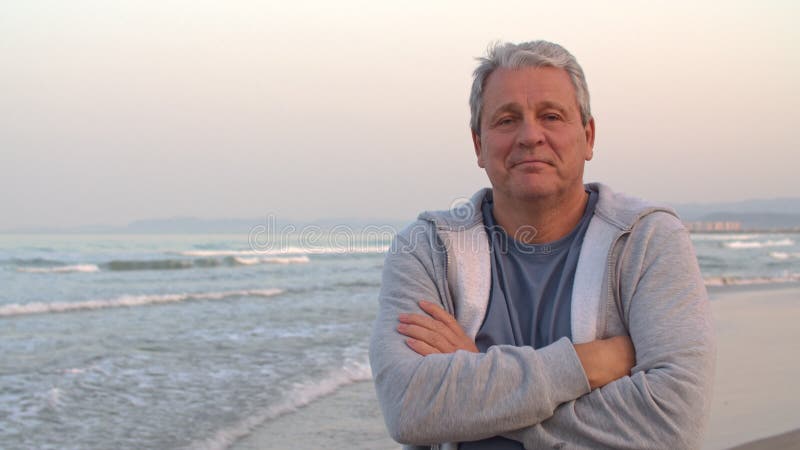 αθλητικός συνταξιούχος με σταυρωμένα χέρια στην παραλία