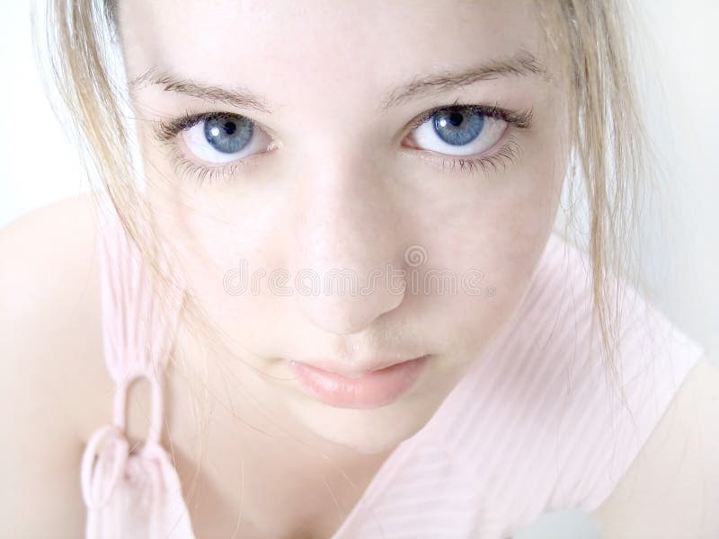 Woman staring into the camera after splashing water over face, high key, pale pink tones, blue eyes. Crisp focus on the eyes. Woman staring into the camera after splashing water over face, high key, pale pink tones, blue eyes. Crisp focus on the eyes.