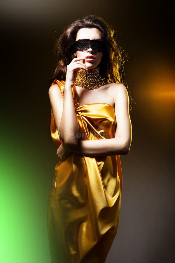 Αισθησιακή ενήλικη γυναίκα στο χρυσό φόρεμα