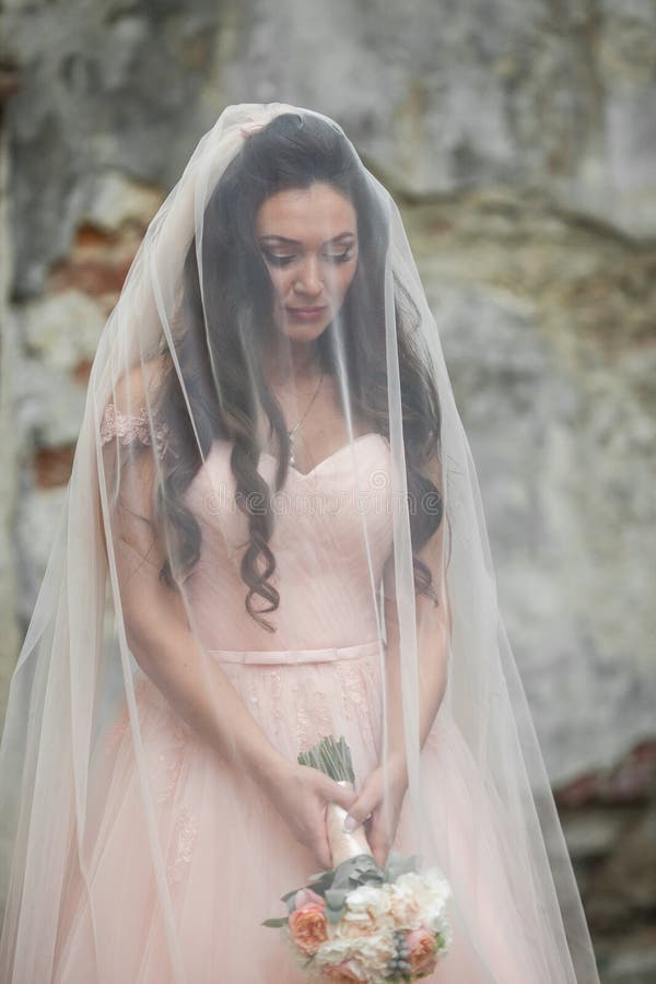 Αισθησιακή όμορφη νύφη brunette που κρατά μια ανθοδέσμη και που κρύβει τα Η.Ε στοκ φωτογραφία με δικαίωμα ελεύθερης χρήσης Αισθησιακή όμορφη νύφη brunette που κρατά μια ανθοδέσμη και που κρύβει τα Η.Ε στοκ φωτογραφία με δικαίωμα ελεύθερης χρήσης