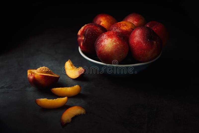 Still life of fresh delicious sweet nectarines with droplets of water in a bowl on dark background. Low key. Place for text, healthy, peach, raw, red, ripe, yellow, agriculture, black, blue, bone, cut, dessert, diet, drops, eat, food, freshness, fruit, group, harvest, ingredient, juicy, knife, natural, orange, organic, peaches, snack, summer, table, tasty, tropical, vitamin, dissected, fruits, half, nobody. Still life of fresh delicious sweet nectarines with droplets of water in a bowl on dark background. Low key. Place for text, healthy, peach, raw, red, ripe, yellow, agriculture, black, blue, bone, cut, dessert, diet, drops, eat, food, freshness, fruit, group, harvest, ingredient, juicy, knife, natural, orange, organic, peaches, snack, summer, table, tasty, tropical, vitamin, dissected, fruits, half, nobody