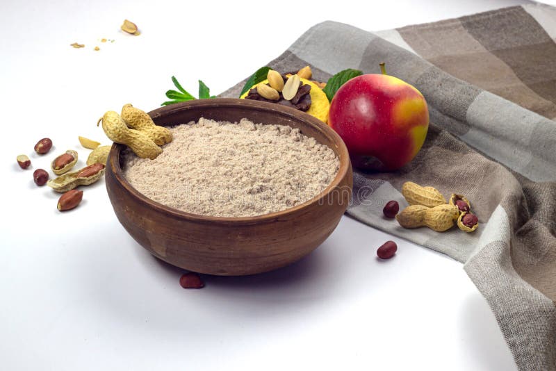 Peanut flour in wooden bowl, apple and cookie with peanut butter on checkered towel isolated on white background. Peanut flour in wooden bowl, apple and cookie with peanut butter on checkered towel isolated on white background