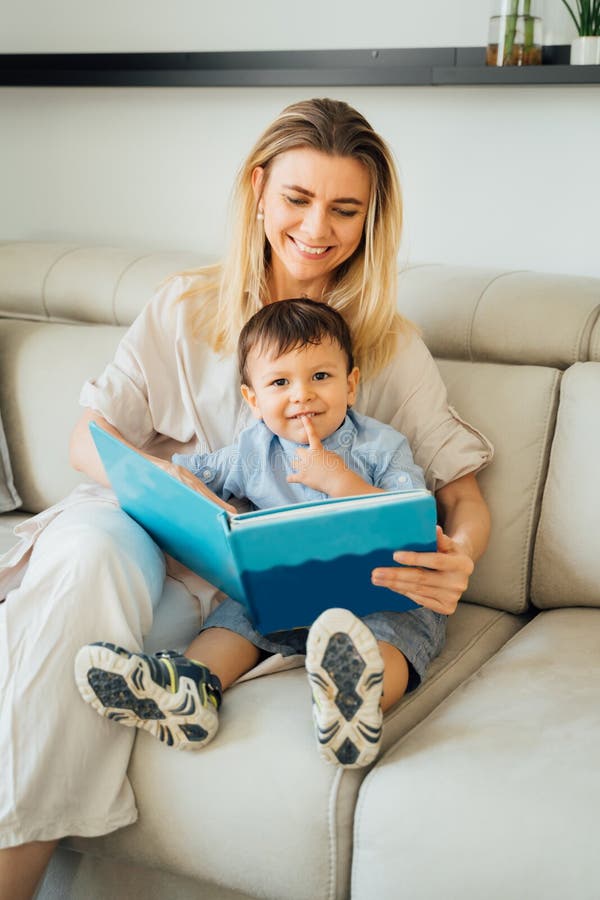 Adorable 2 years old boy looking at camera and smile. Reading with kid. Beautiful smiling blond women holding book playing with son. Relaxed time with family. upbringing and education. vertical. Adorable 2 years old boy looking at camera and smile. Reading with kid. Beautiful smiling blond women holding book playing with son. Relaxed time with family. upbringing and education. vertical