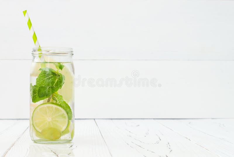 Refreshing homemade lime and mint cocktail over old vintage wooden table. Detox fruit infused flavored water. Clean eating. Copy space background. Refreshing homemade lime and mint cocktail over old vintage wooden table. Detox fruit infused flavored water. Clean eating. Copy space background