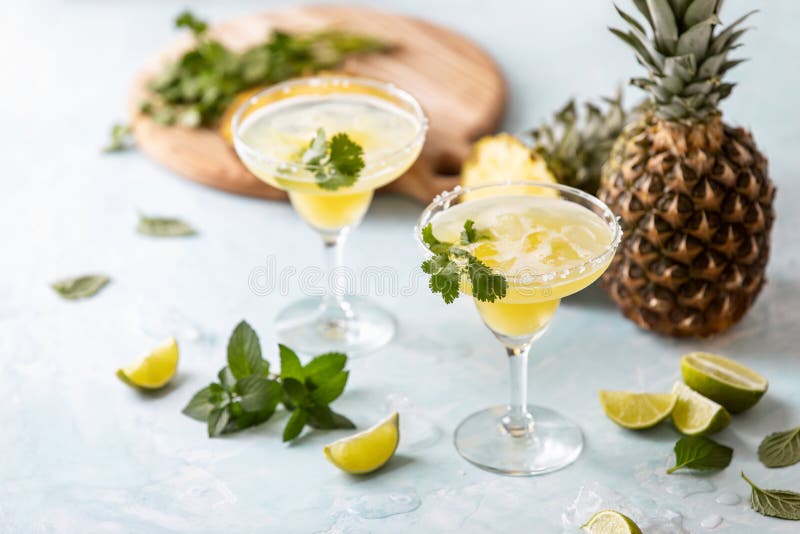 Pineapple coriander infused margarita in glasses with ingredients, front view. Pineapple coriander infused margarita in glasses with ingredients, front view