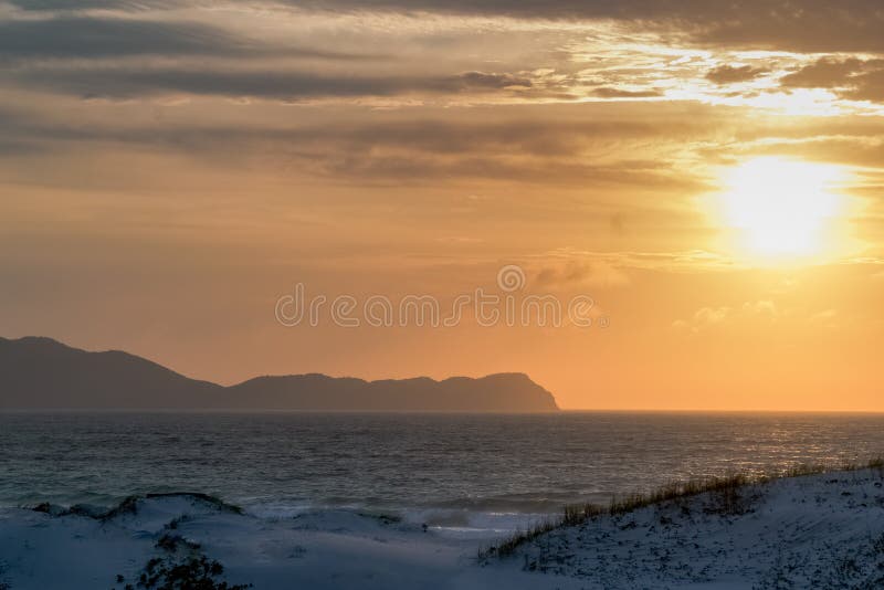 ανατολή του ήλιου στην άκρη της praia das dunas όμορφος χρυσός ουρανός και πολλά βουνά στο φόντο. στοκ φωτογραφία με δικαίωμα ελεύθερης χρήσης