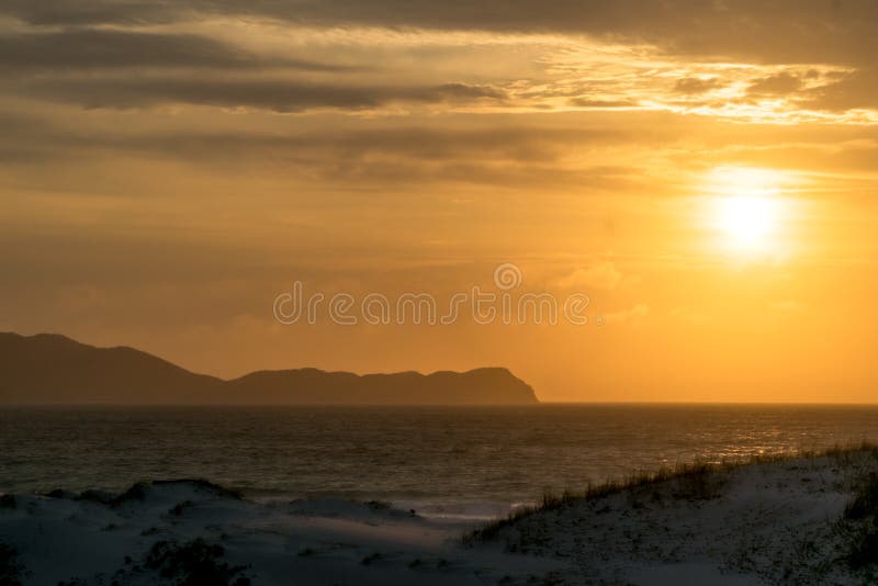 ανατολή του ήλιου στην άκρη της praia das dunas όμορφος χρυσός ουρανός και πολλά βουνά στο φόντο. στοκ φωτογραφία με δικαίωμα ελεύθερης χρήσης