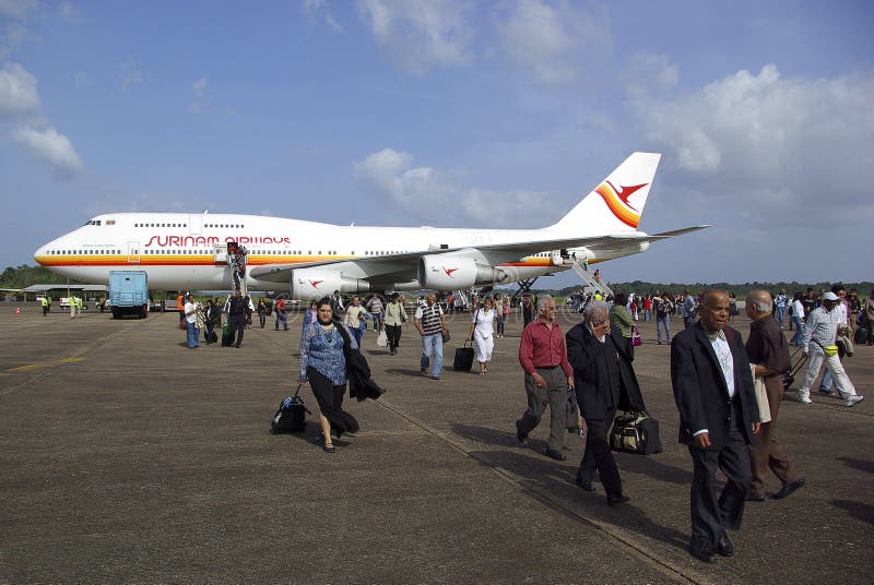 Passengers depart aeroplane and walk to the arrival terminal to check in to Suriname. Passengers depart aeroplane and walk to the arrival terminal to check in to Suriname